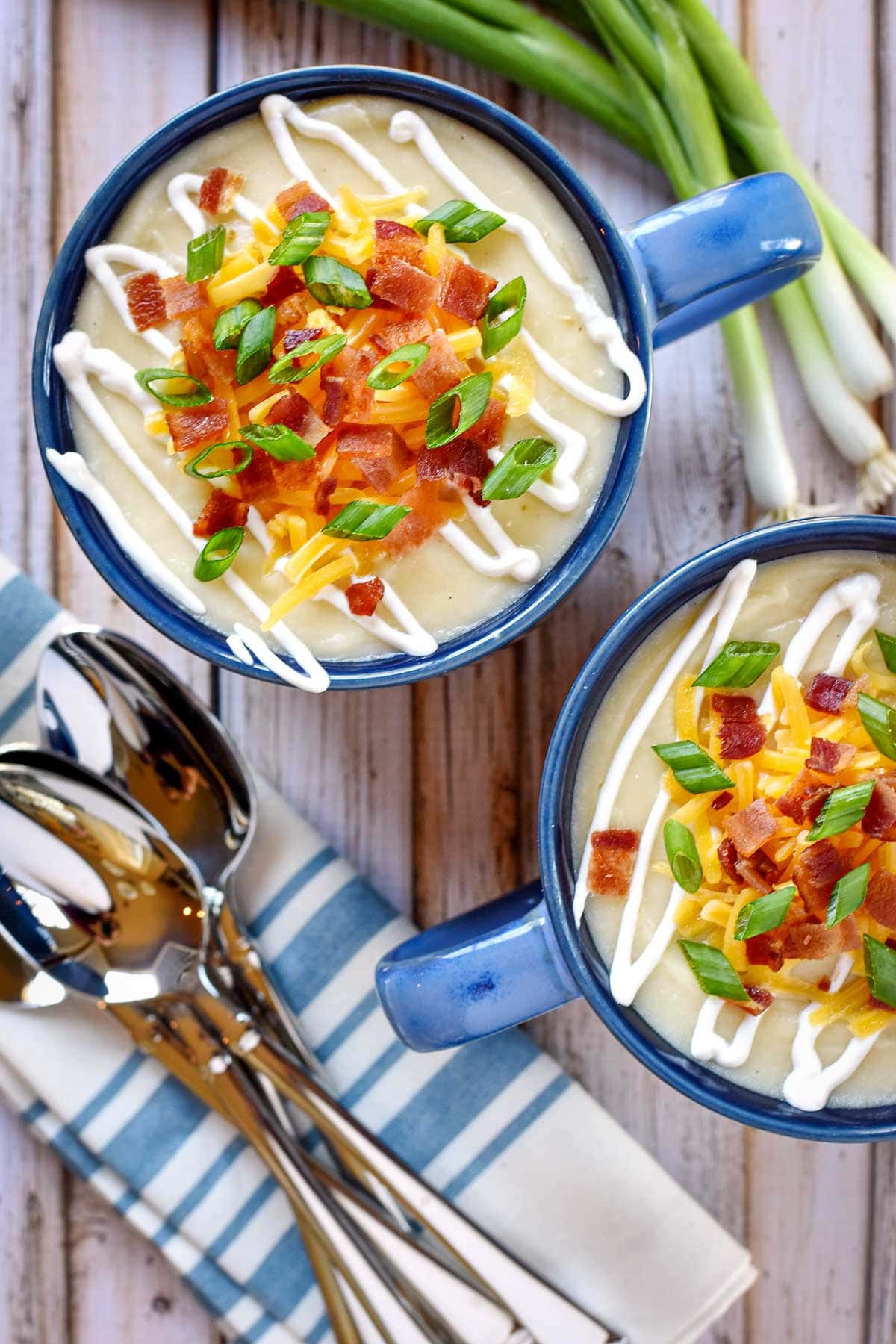 Aerial view of two bowls of Baked Potato Soup with toppings.