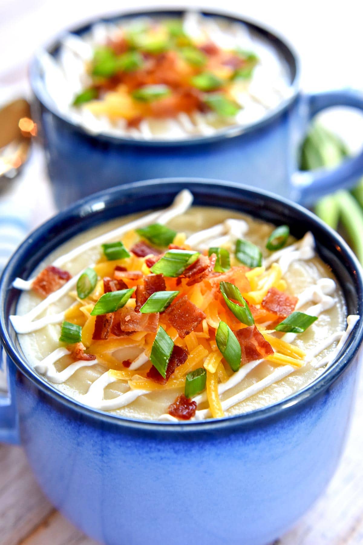 Baked Potato Soup garnished with sour cream, cheese, bacon, and green onions.