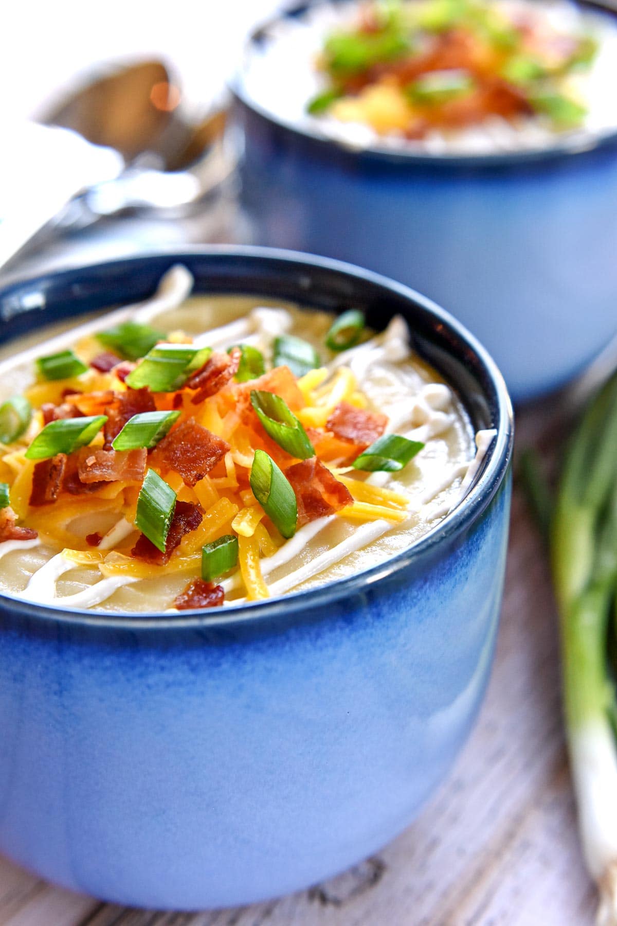 Loaded Baked Potato Soup garnished with cheese, bacon, and more.