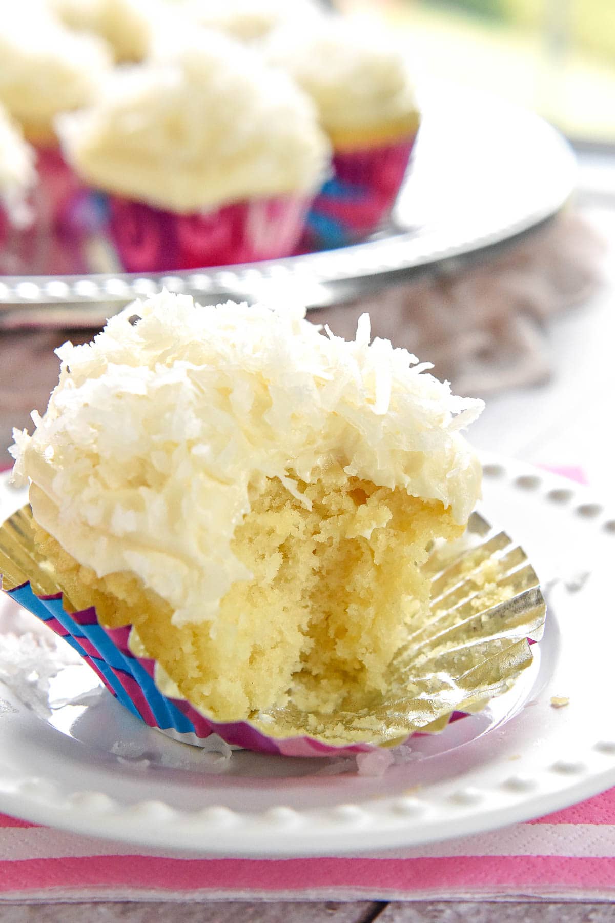 Coconut Cupcakes with liner pulled down and missing bite.