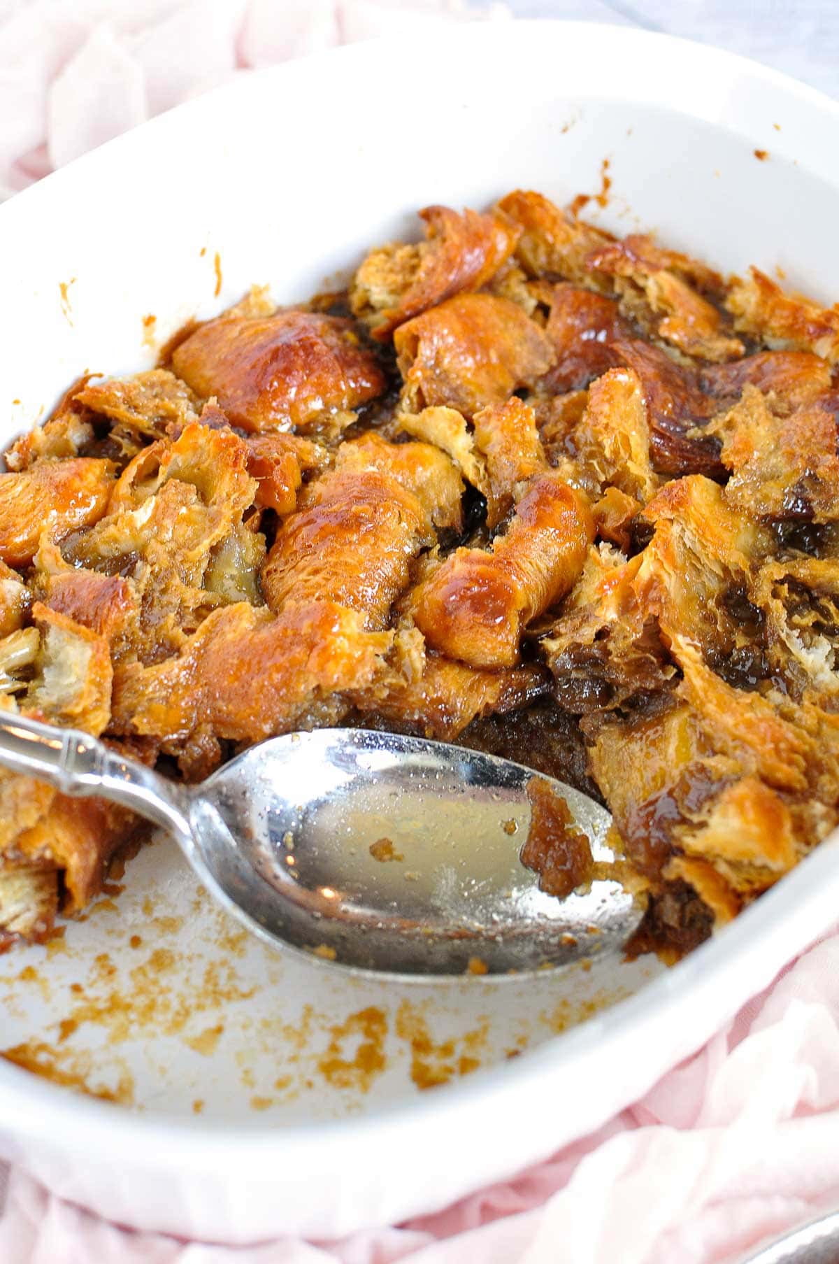 Croissant Bread Pudding in baking dish with missing portion scooped out.