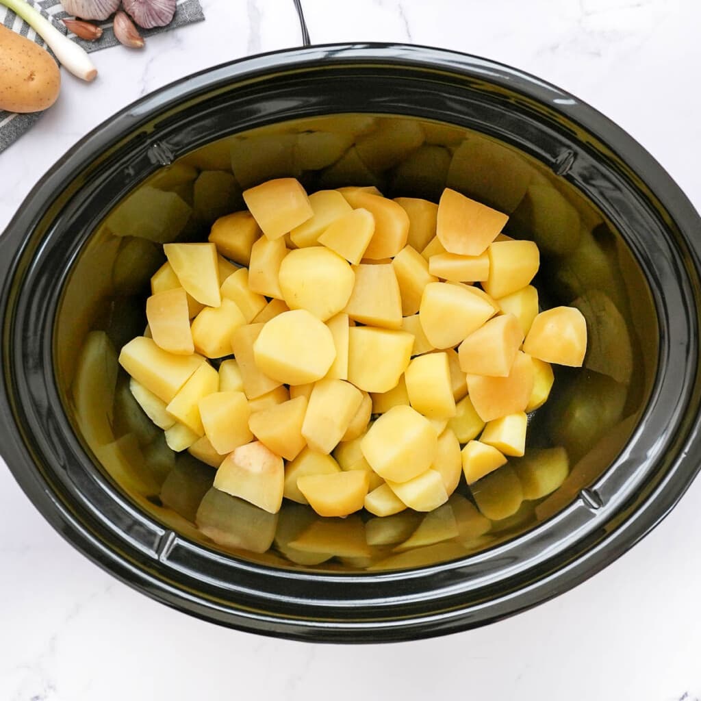 Potatoes in slow cooker for baked potato soup crock pot.