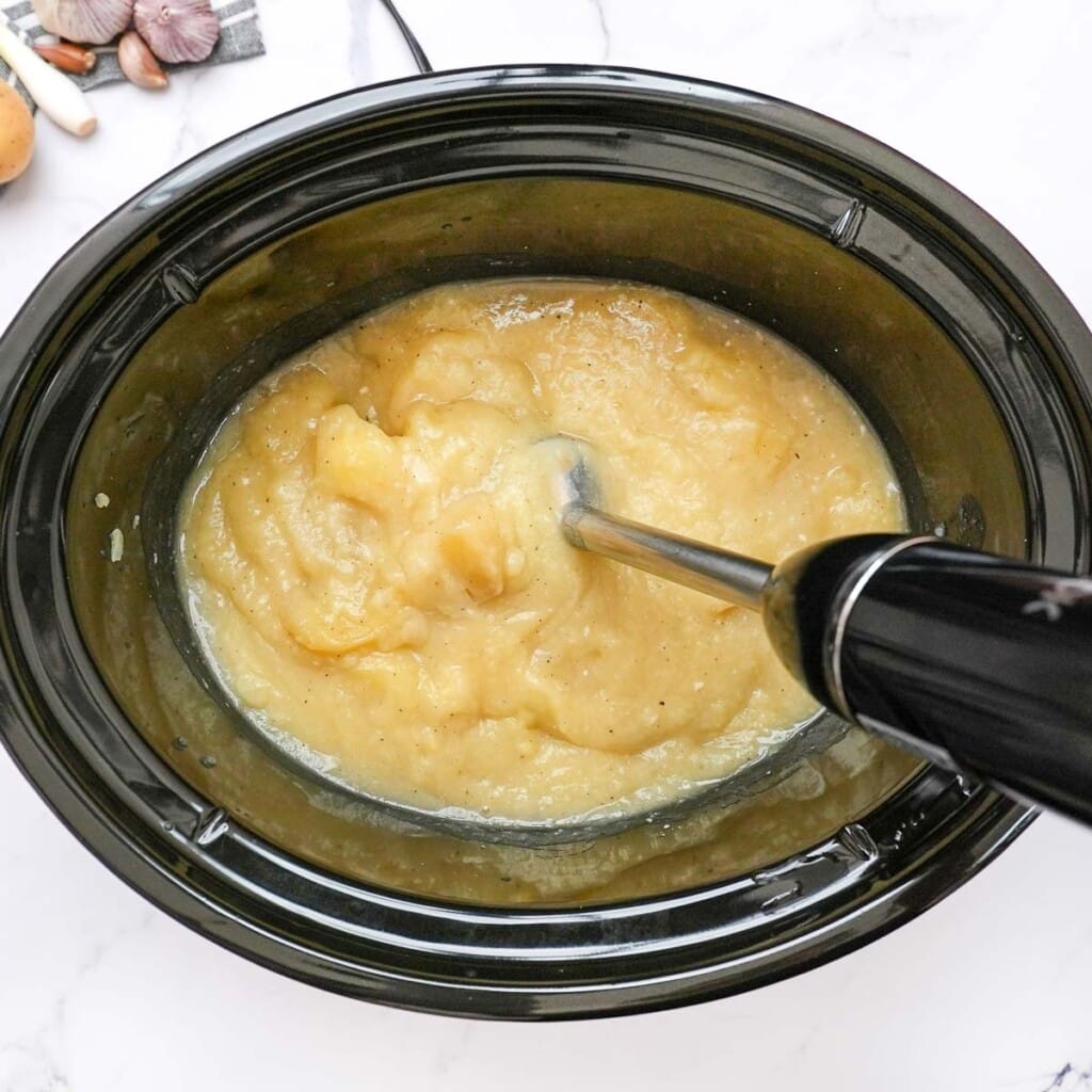 Pureeing crock pot loaded baked potato soup in slow cooker.