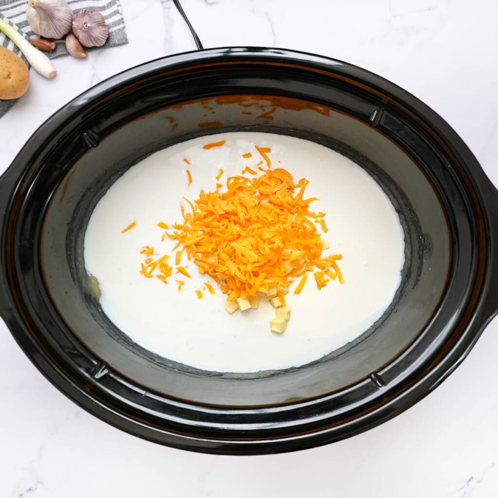 Adding grated cheddar cheese to slow cooker.