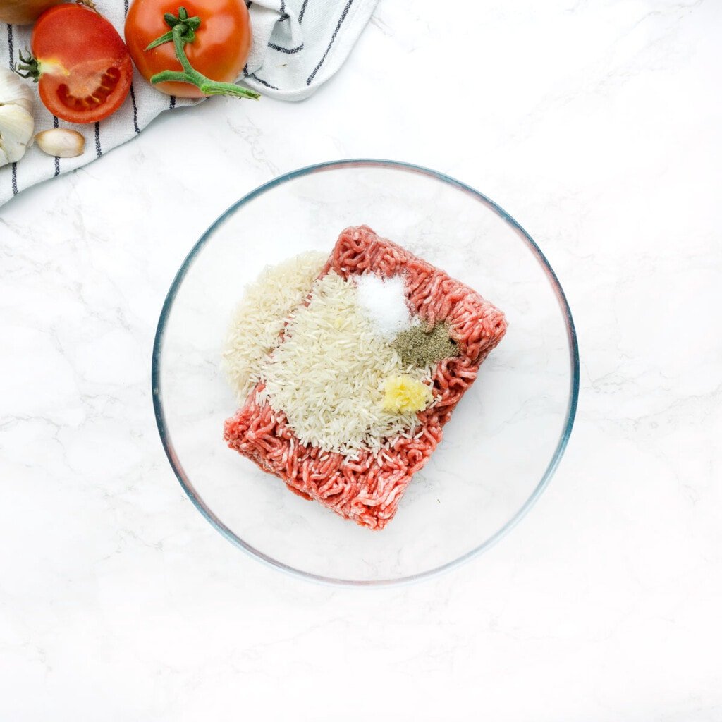 Ground beef, rice, and seasonings in bowl.