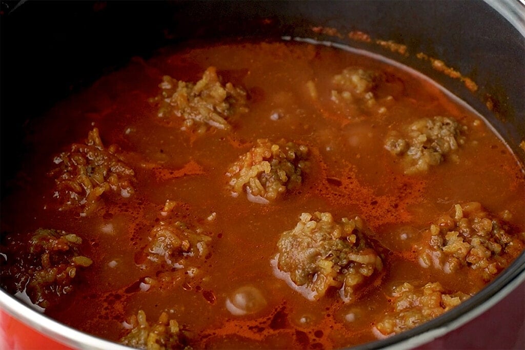 Porcupine Meatballs cooked and floating in tomato sauce.