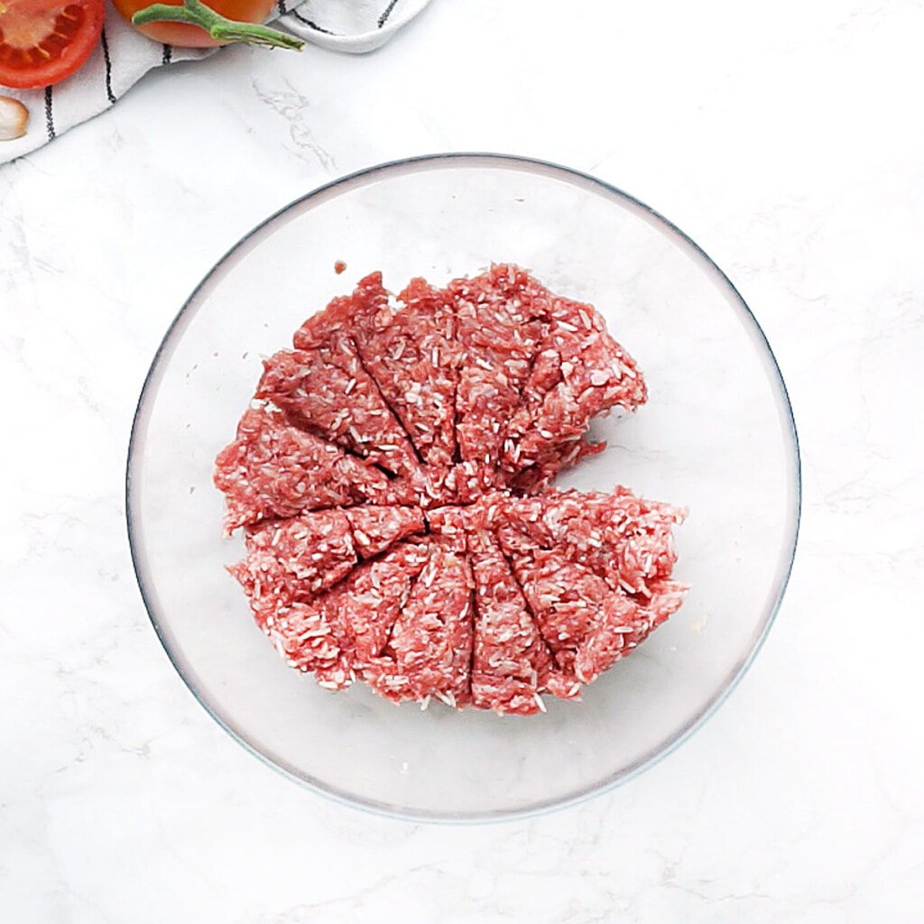 Ground beef mixture in bowl divided into 12 sections.