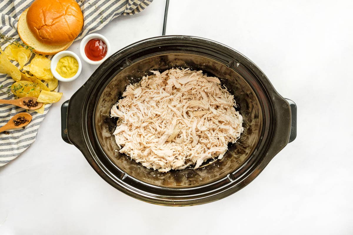 Shredded chicken in slow cooker to make Chicken Sloppy Joes.