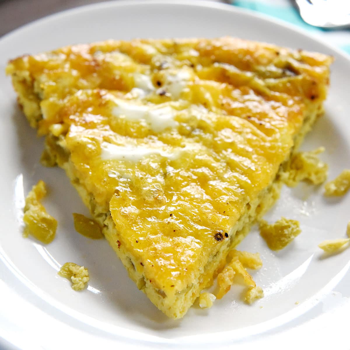 Easy Egg Bake, slice on plate with cheddar cheese and green chiles.