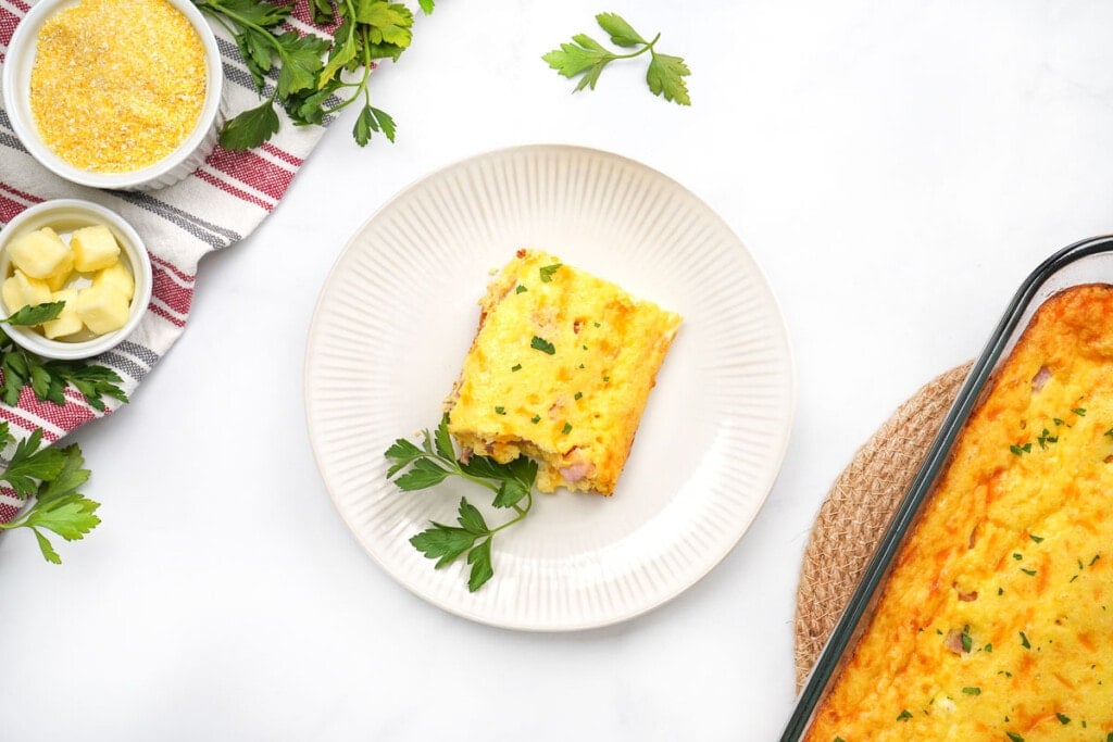 Breakfast casserole with grits on plate and in baking dish.