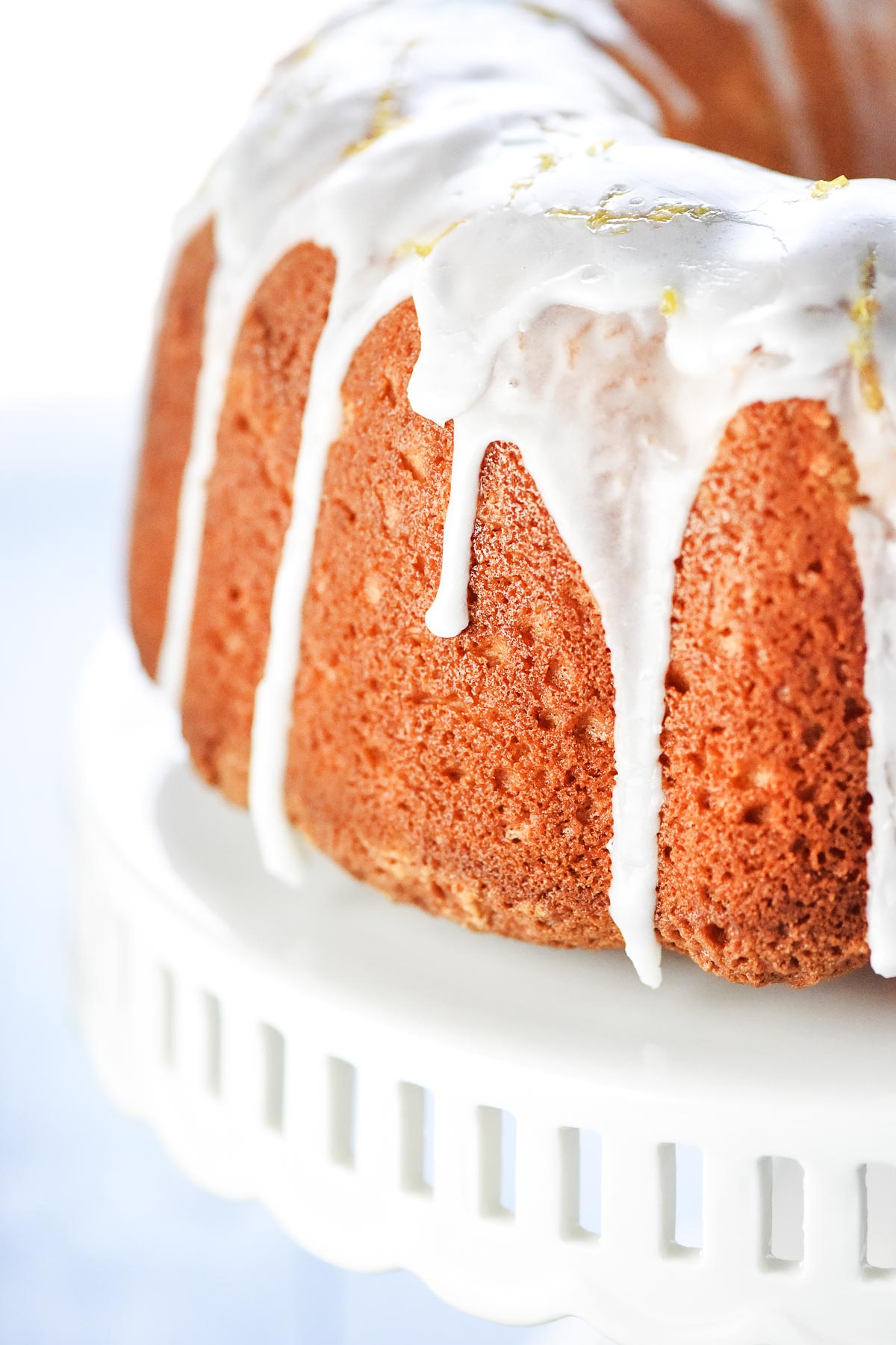 Lemon Pound Cake on cake stand with lemon glaze dripping down.