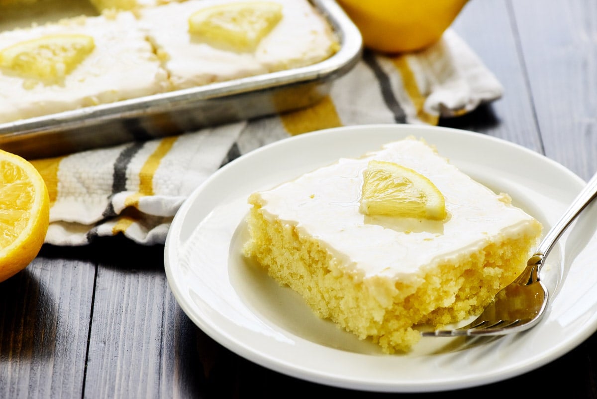 Lemon Sheet Cake on plate and in pan, topped with lemon glaze for cake.