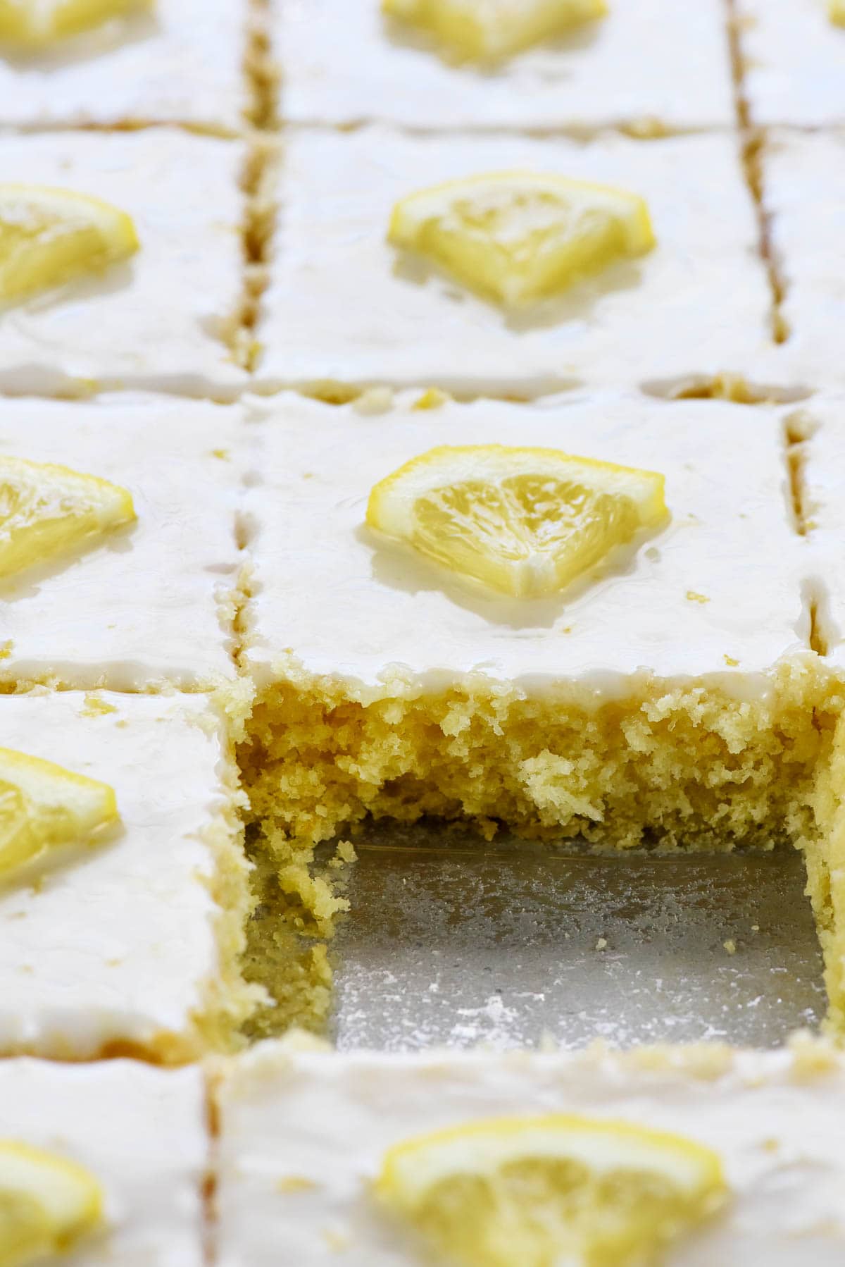 Lemon Sheet Cake with missing piece in pan.