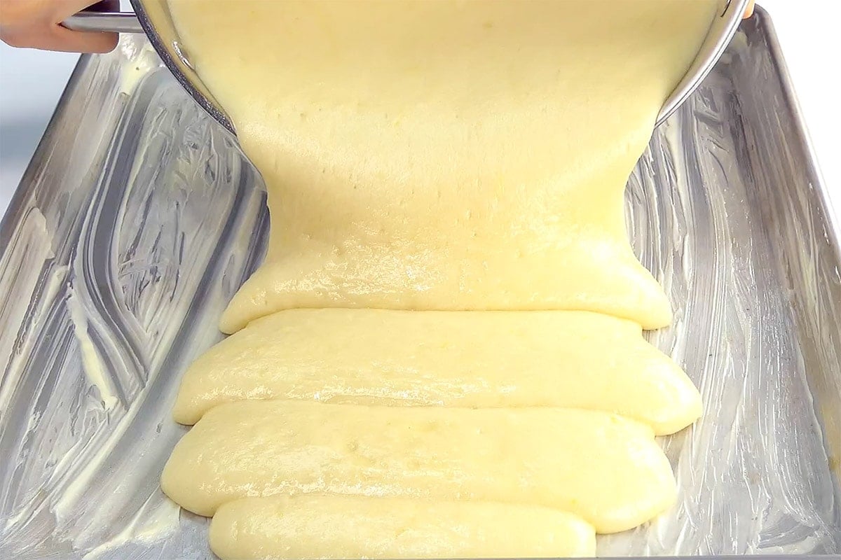 Pouring lemon cake recipe into sheet pan.