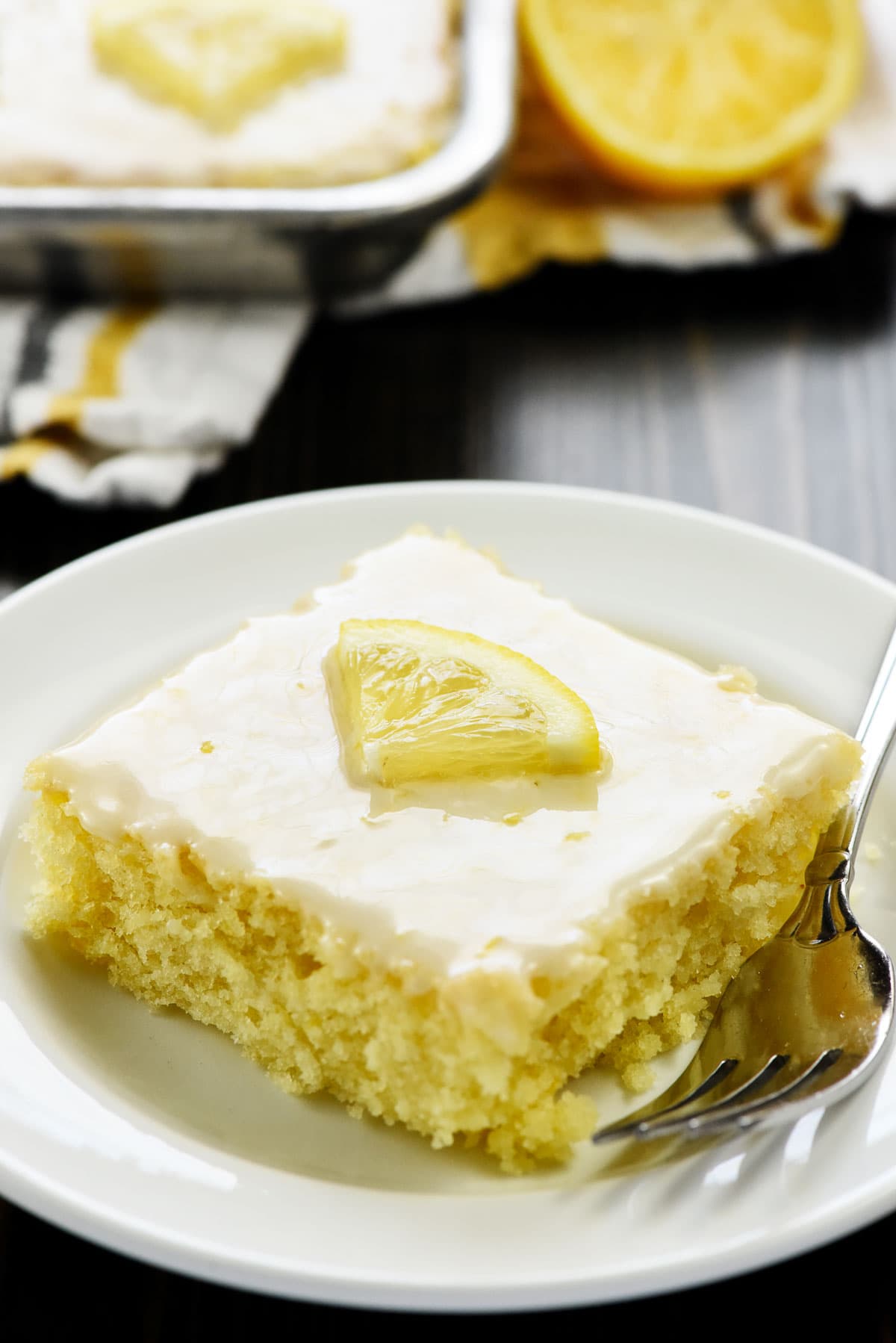 Slice of Lemon Sheet Cake with lemon glaze on plate.