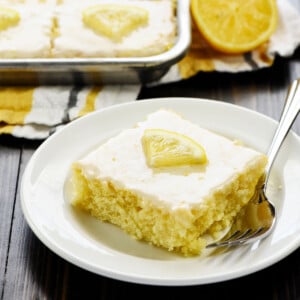 Lemon Sheet Cake with lemon glaze on plate with fork with pan in background.