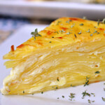 Scalloped Potato Flan slice on plate with fresh thyme.