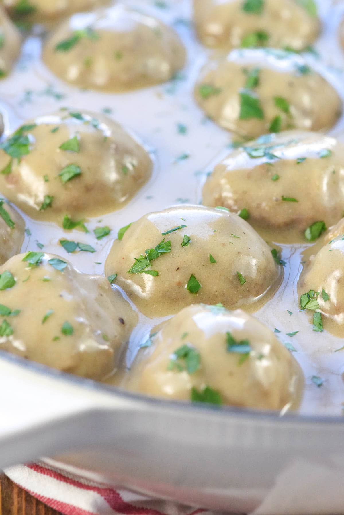 Close-up of Swedish Meatballs in skillet garnished with parsley.