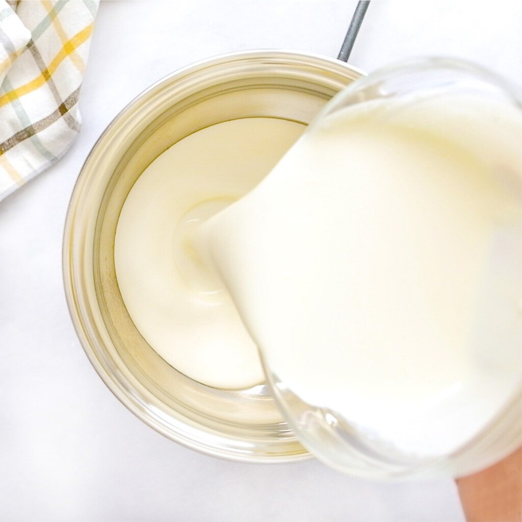 Pouring heavy cream into pot.