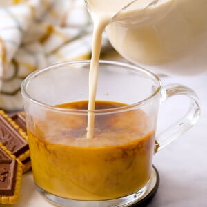 Vanilla Coffee Creamer being poured into coffee in clear glass mug.