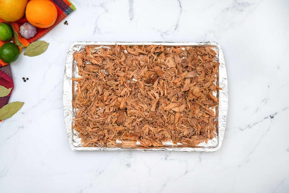 Pork carnitas recipe on pan ready to caramelize under the broiler.