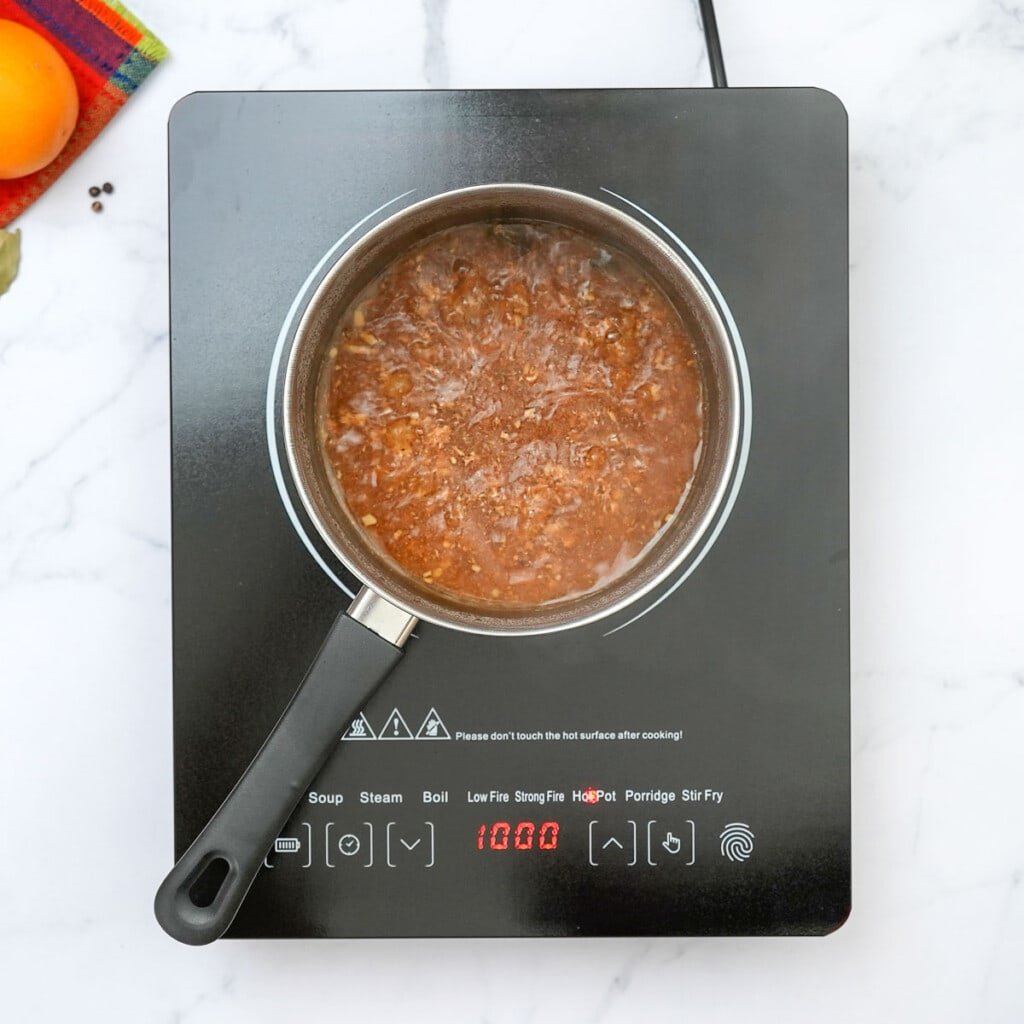 Bringing pot of cooking liquids to a boil for carnitas recipe slow cooker.