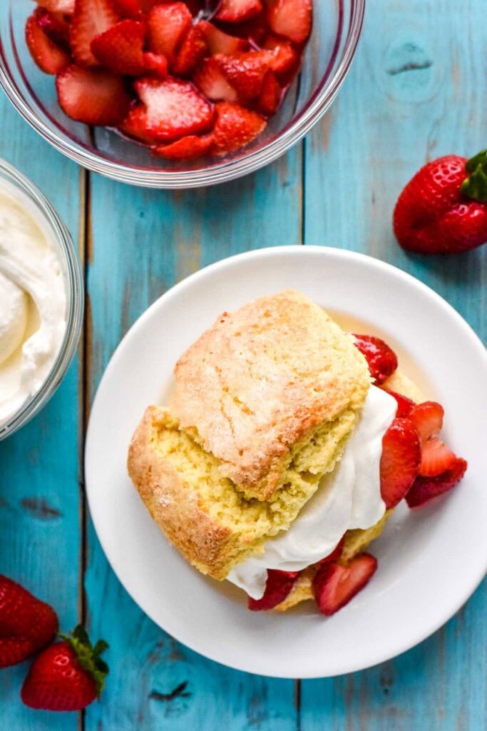 Adding top shortcake over whipped cream and berries.