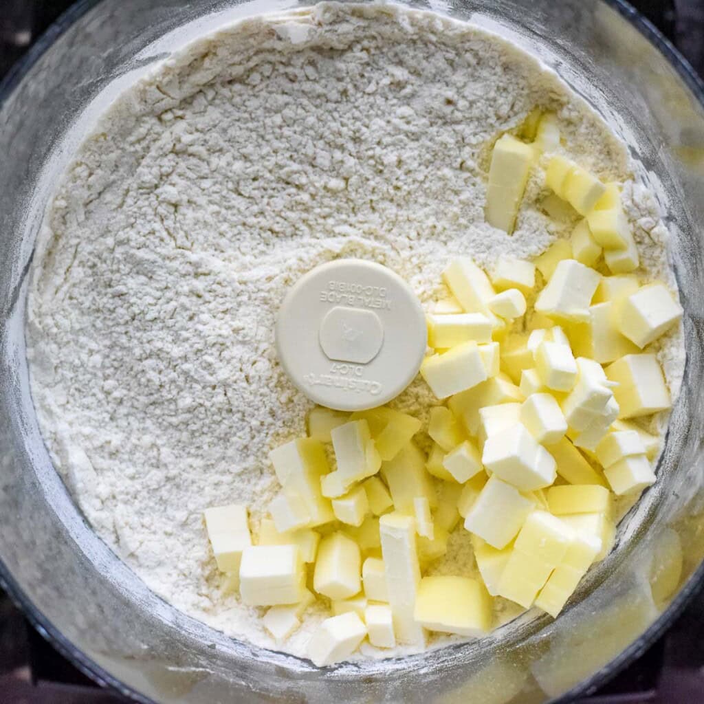 Adding butter to dry ingredients in food processor for shortcake recipe.