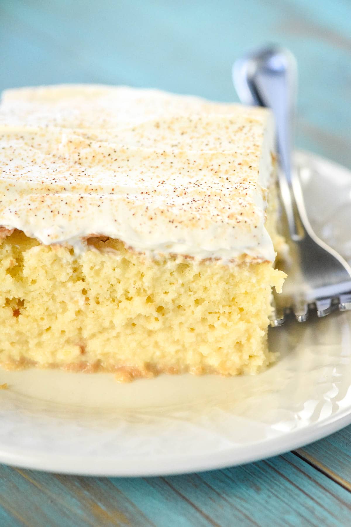 Slice of Tres Leches Cake recipe on plate with fork.