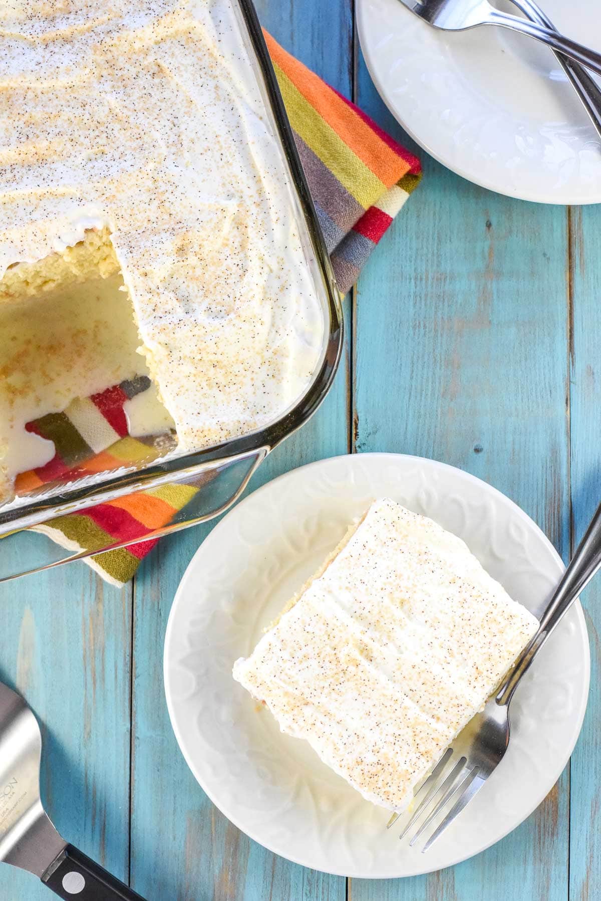 Aerial view of Tres Leche Cake on plate and in dish with missing piece.