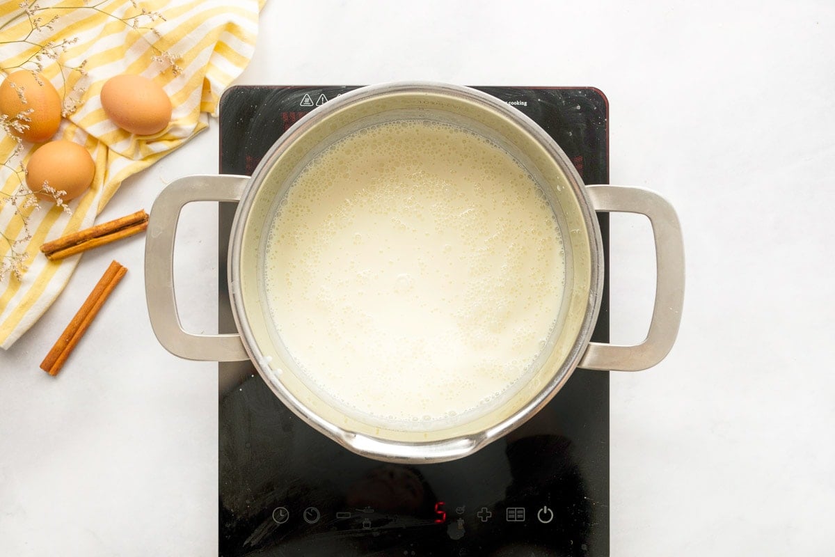 Bringing the three milks to a simmer in a pot.