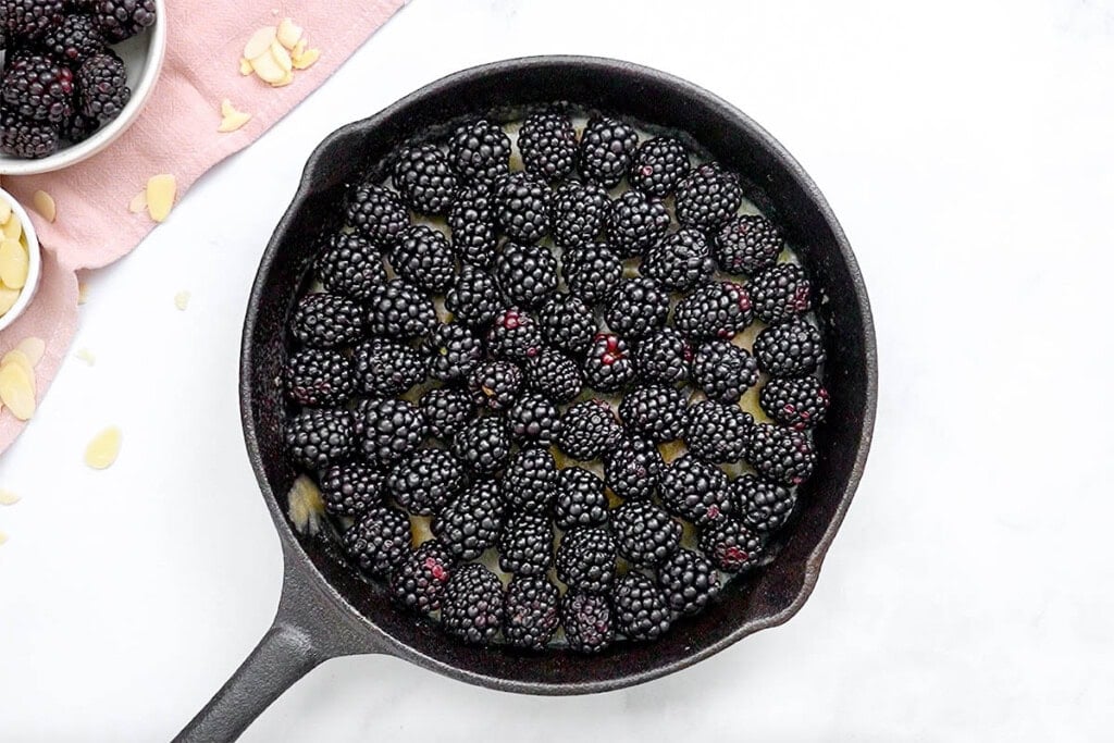 Blackberries arranged over butter and brown sugar in skillet.