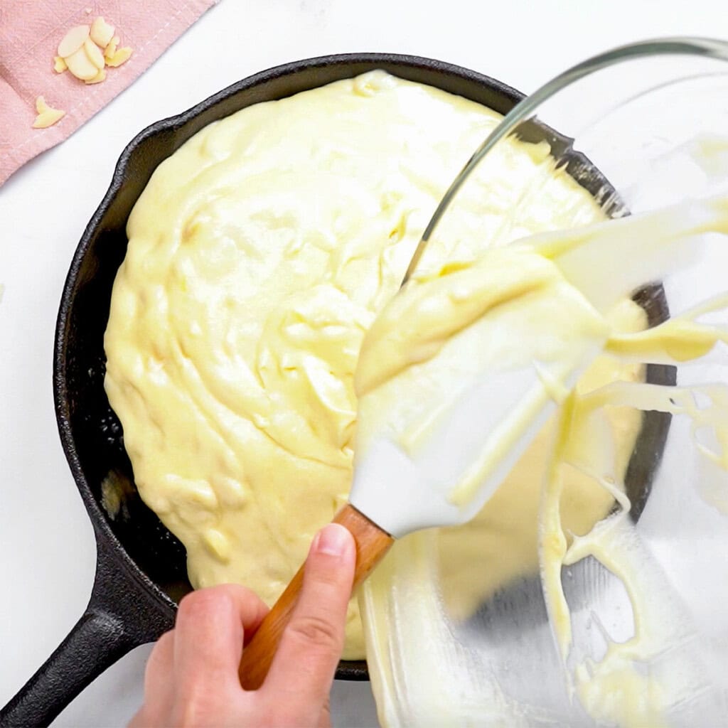 Pouring batter over blackberries for blackberry upside-down cake.