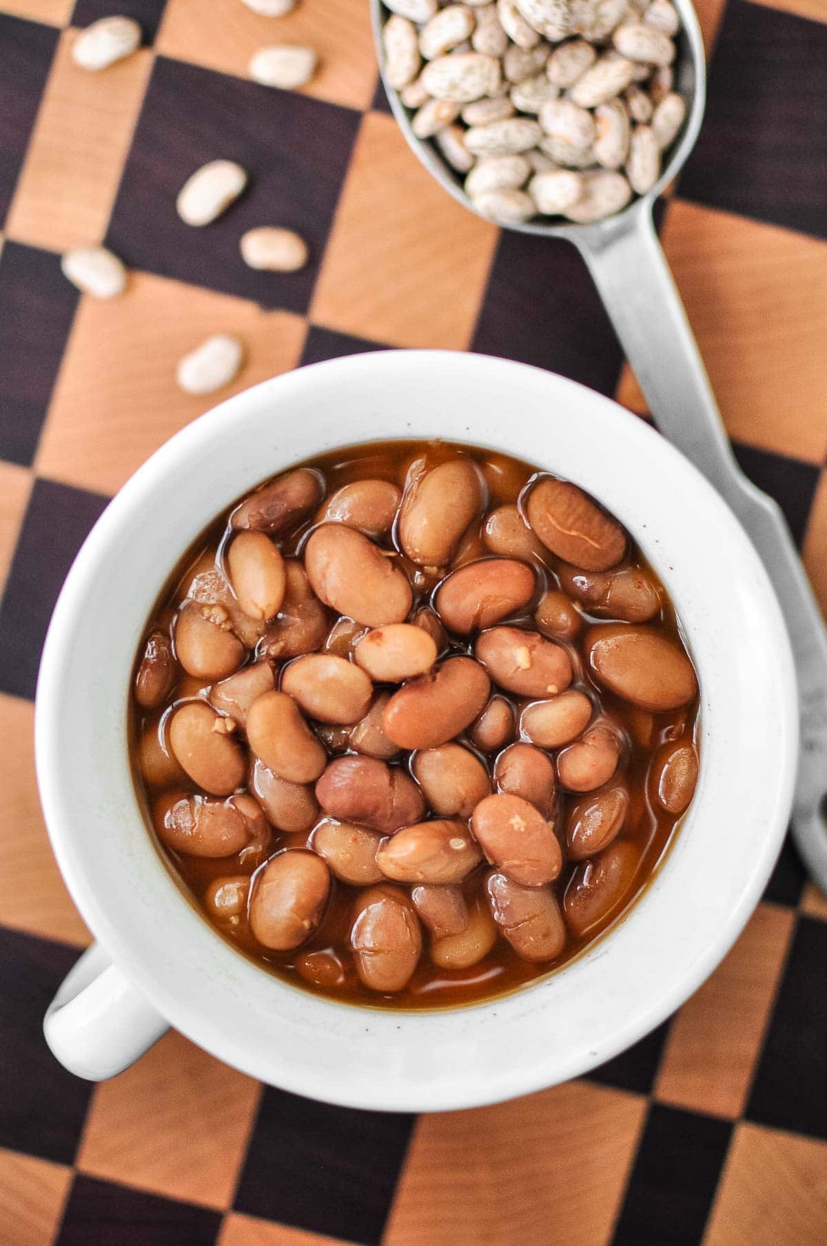 Ranch Style Beans in bowl with dried pinto beans on table.