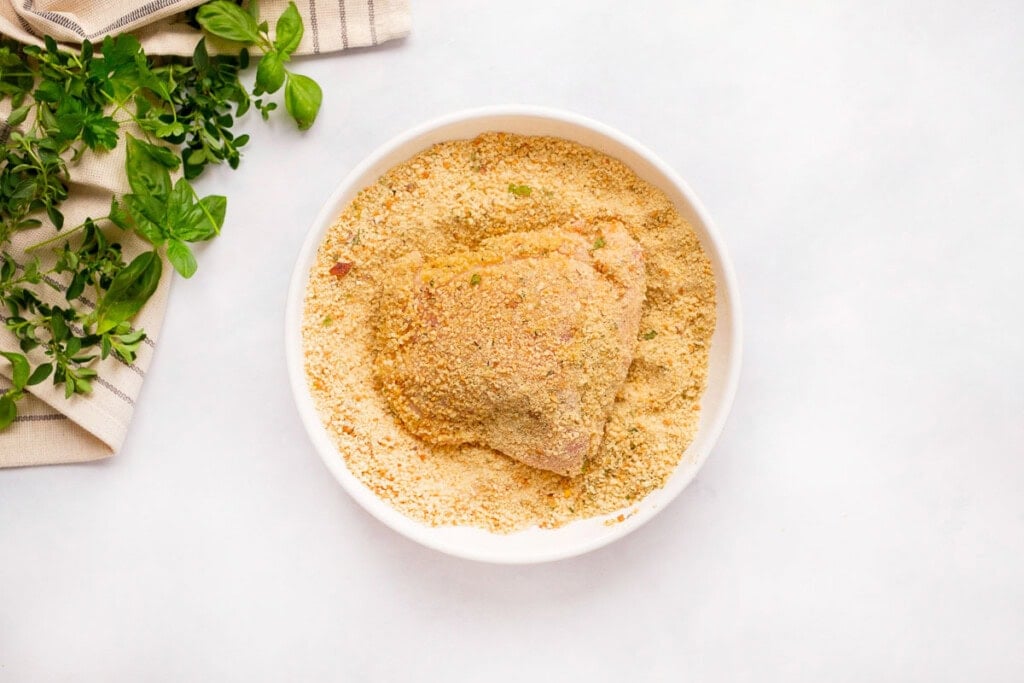 Dipping chicken in oil and then seasoned breadcrumbs.