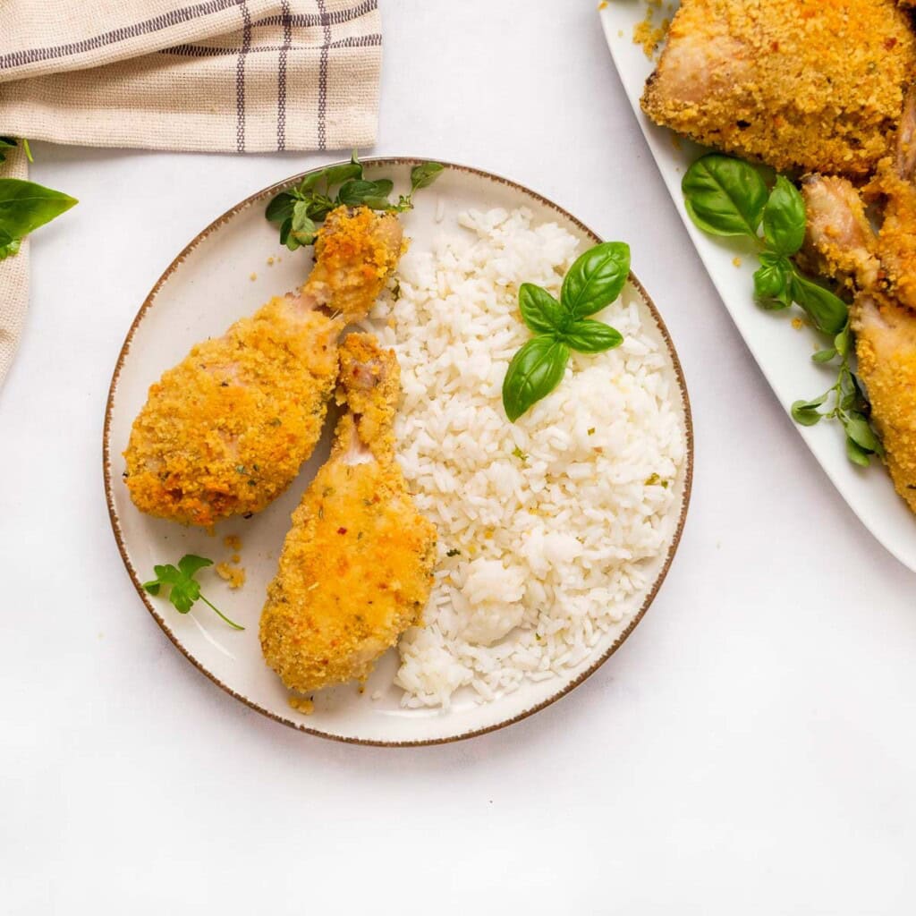 Italian baked chicken drumsticks on plate with rice.
