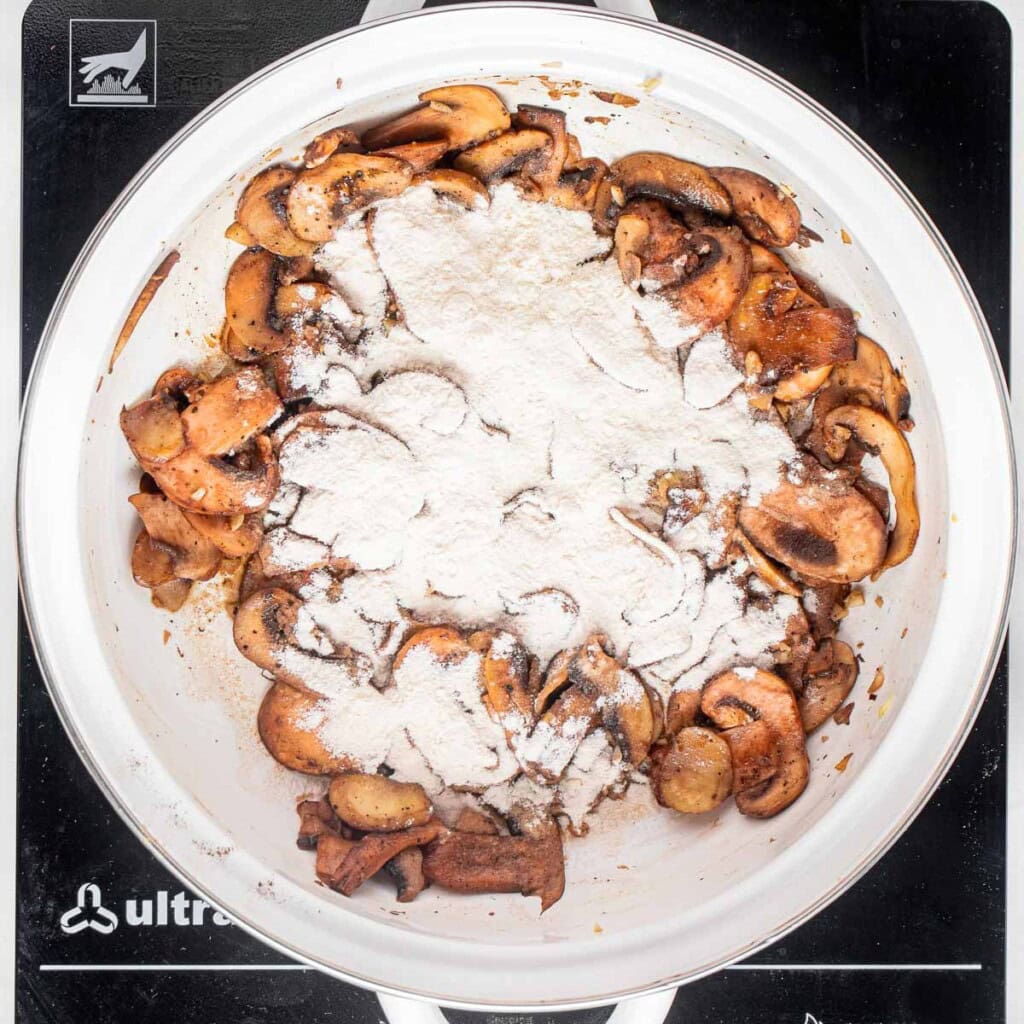 Adding flour to sauteed mushrooms.