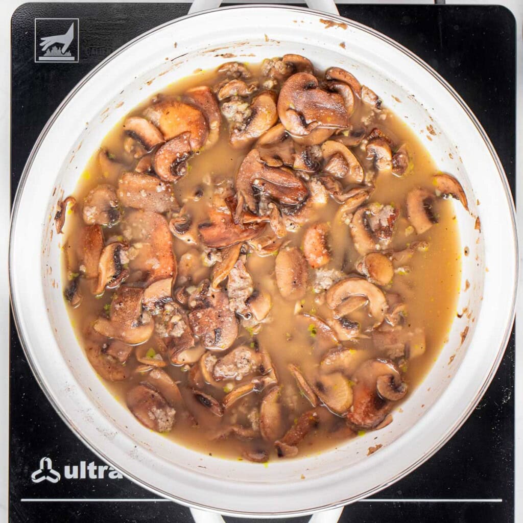 Adding broth to sauteed fresh mushrooms.