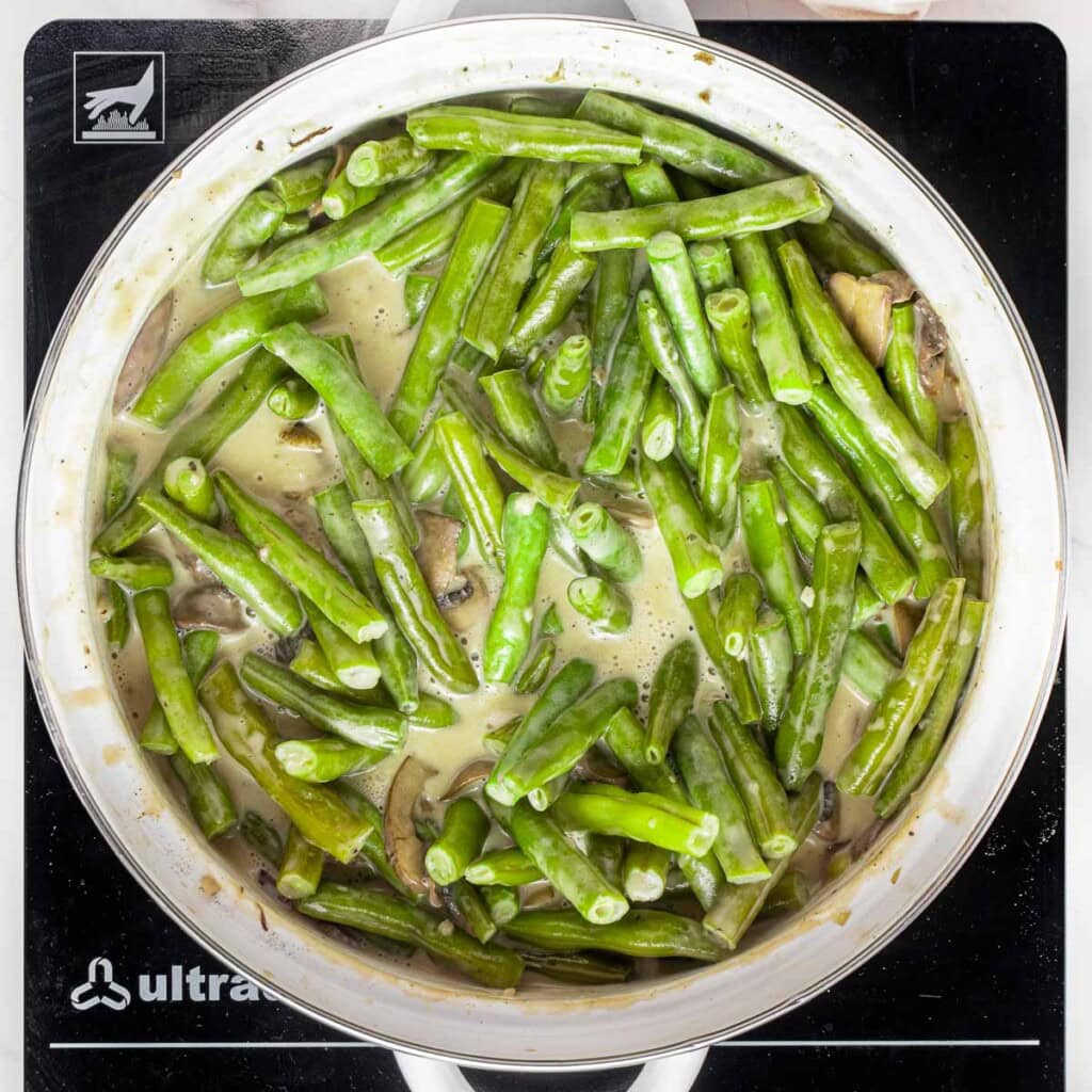 Mixture in pot for green bean casserole with fresh green beans.