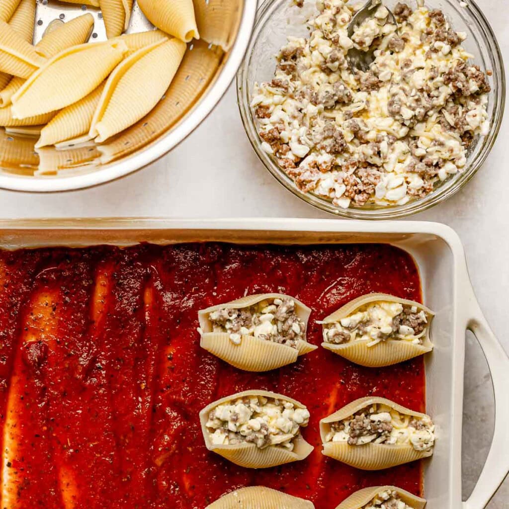 Assembling stuffed shells recipe with meat.