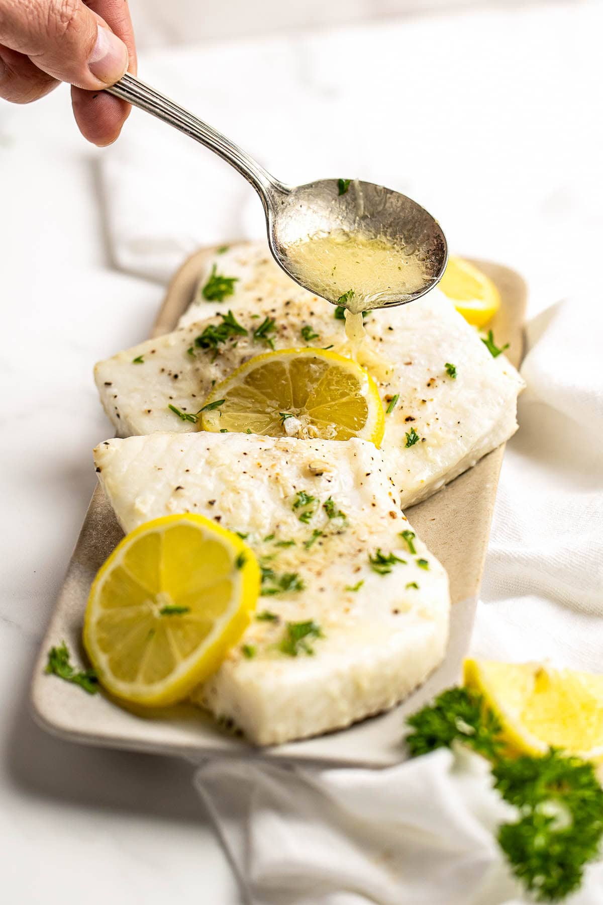 Drizzling lemon garlic butter over Baked Halibut.