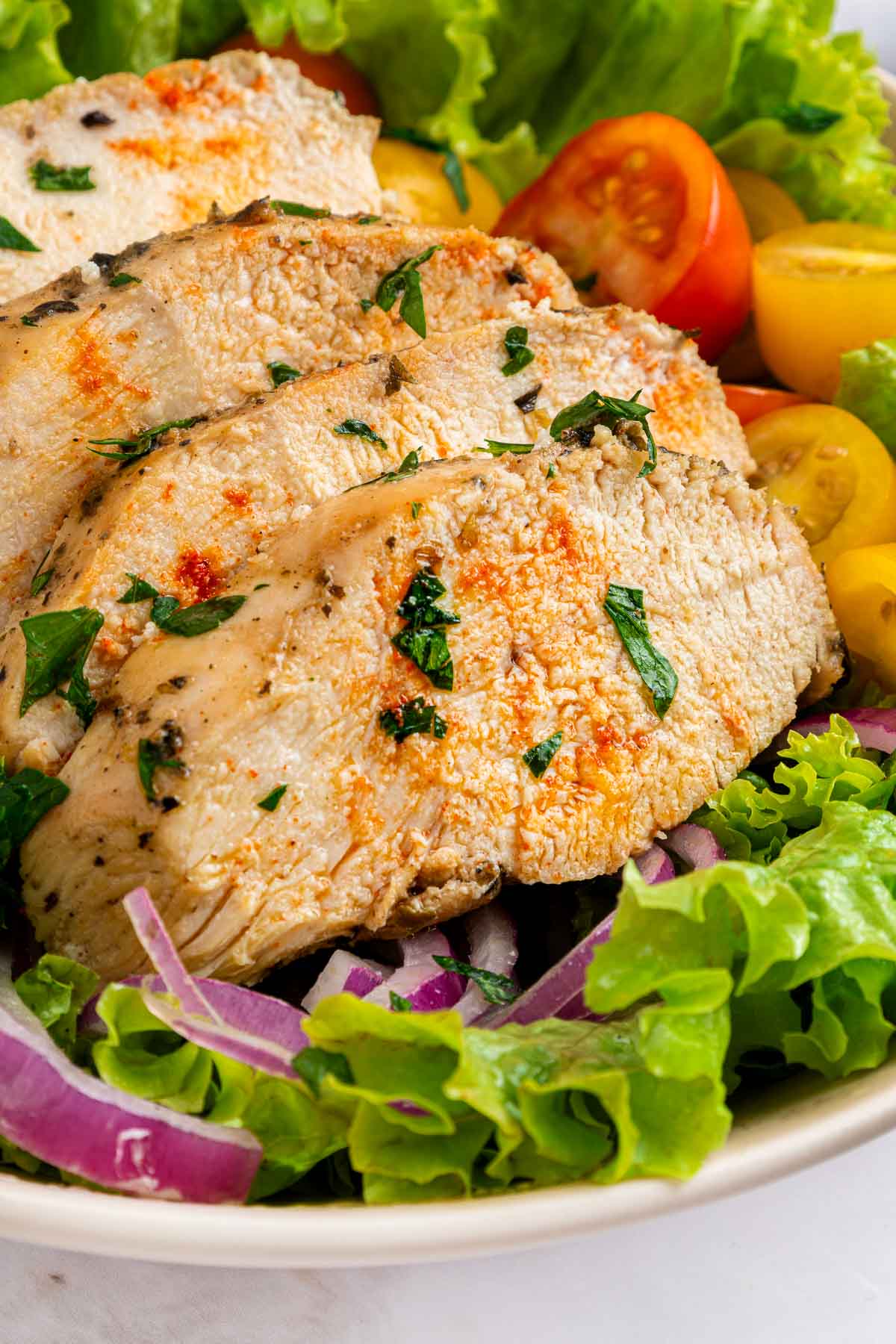 Mediterranean Chicken Marinade close-up of chicken slices over a salad.