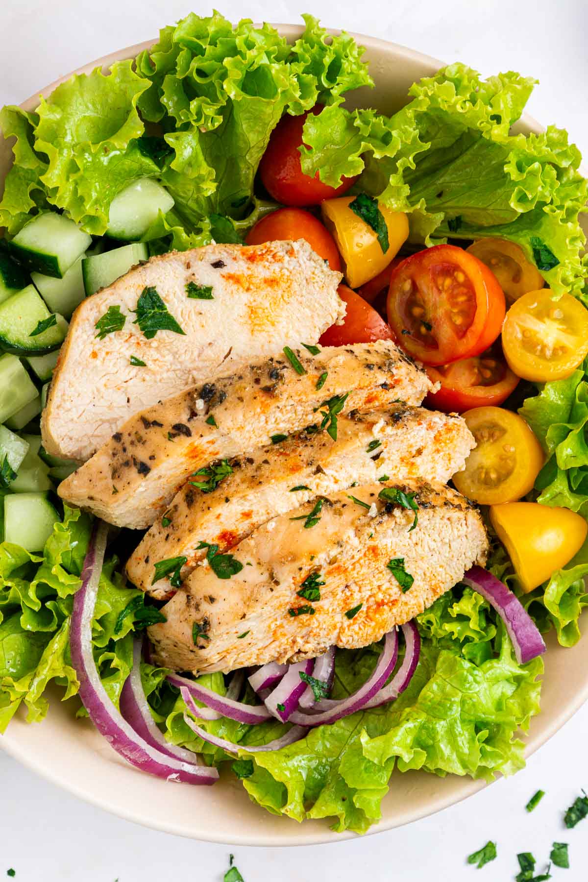 Aerial view of Mediterranean Chicken Marinade chicken slices on salad.