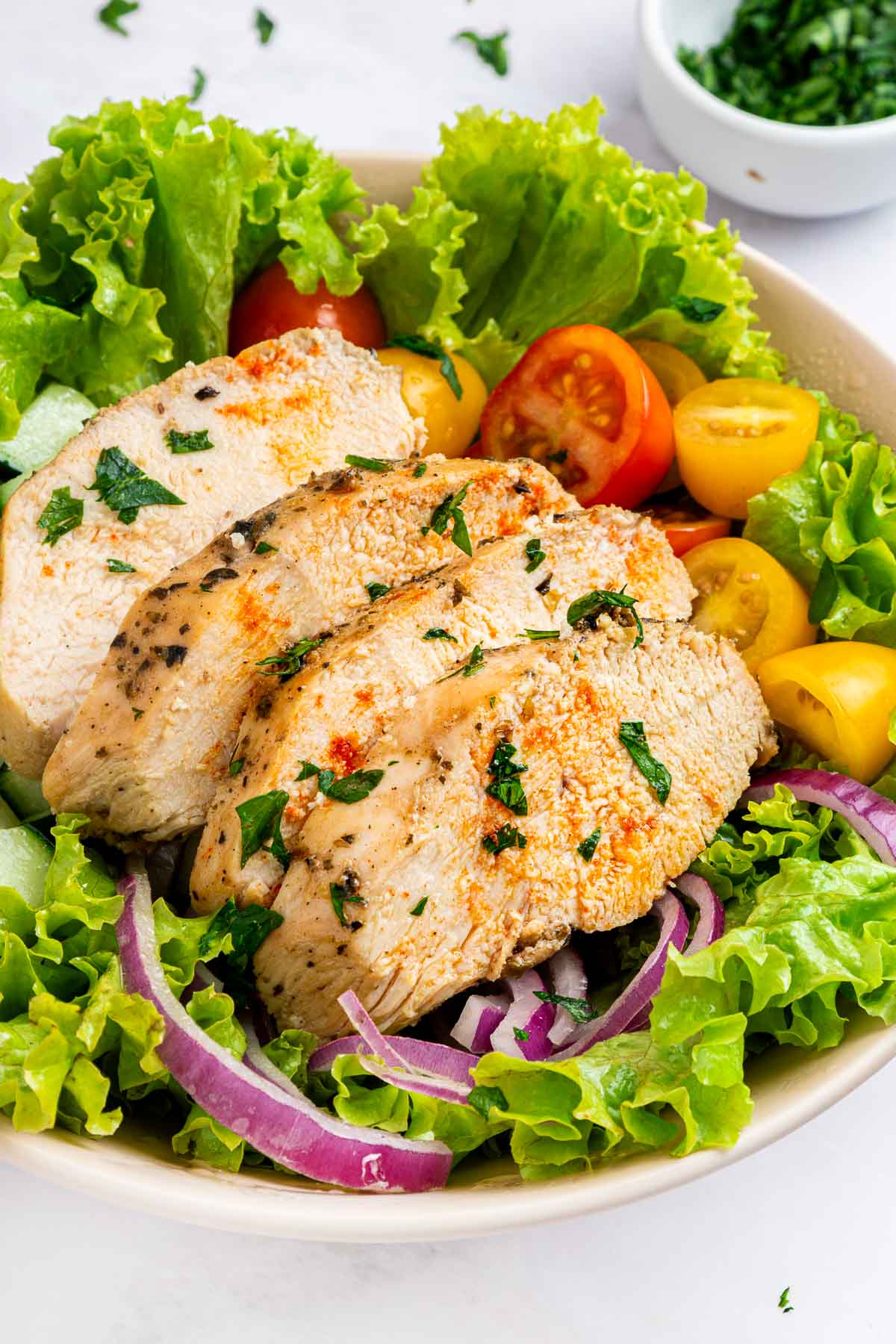 Sliced chicken made with Mediterranean Chicken Marinade on salad.