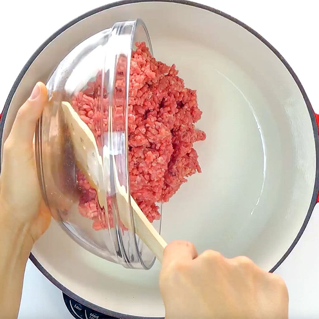 Adding ground beef to pot for one of the best ground beef and rice recipes.
