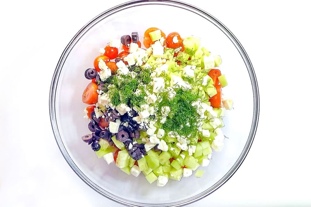Adding dill to cucumber feta tomato salad.