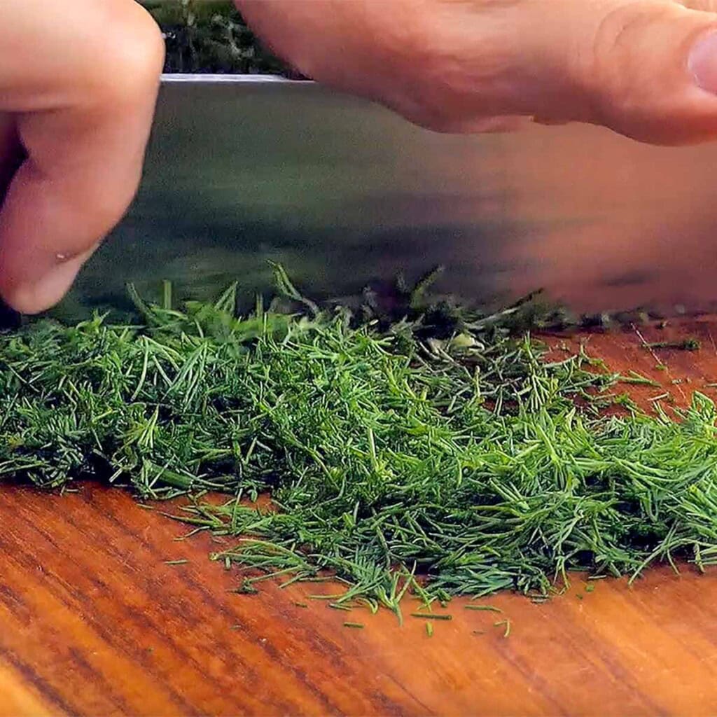 Chopping dill for tomato cucumber salad.