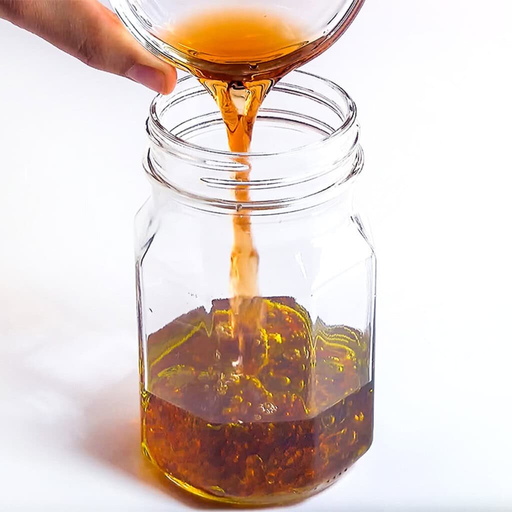 Adding oil and vinegar to jar for dressing.