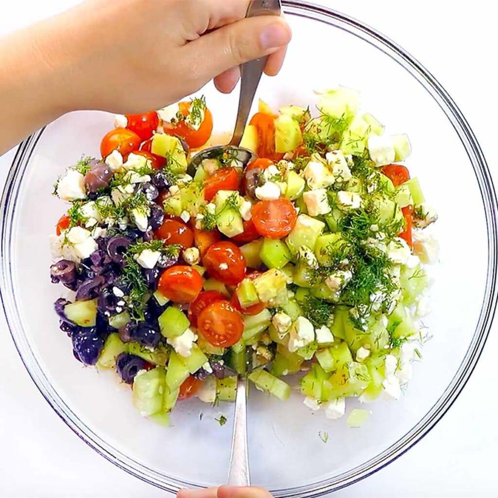 Tossing tomato and cucumber and feta salad.