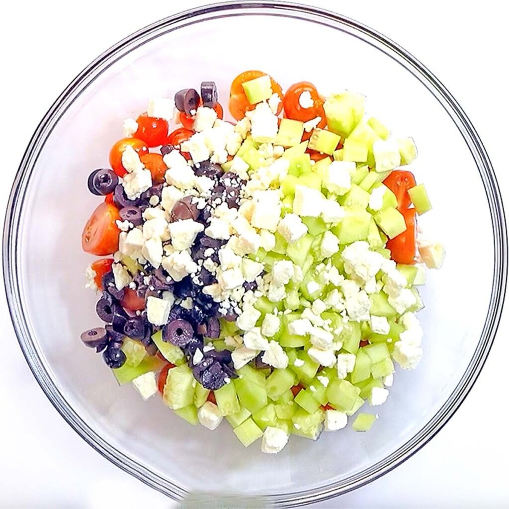 Adding feta to cucumber and tomato feta salad.